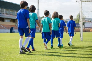Niños de la escuela deportiva caminando hacia el campo de entrenamiento